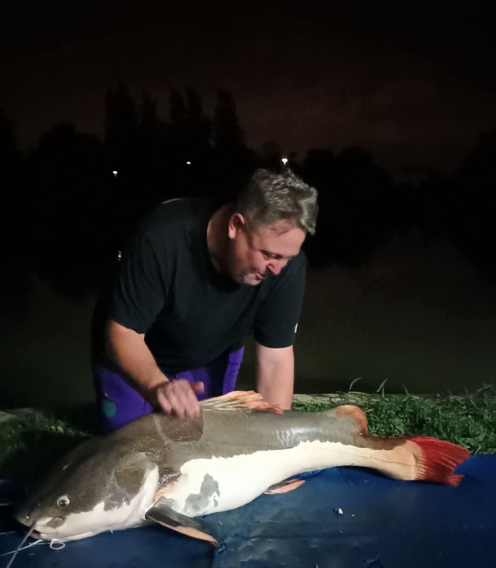Khun Paul with a redtail catfish at night